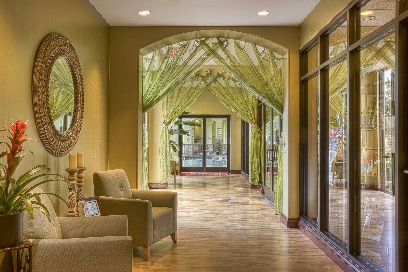 Luxurious hotel hallway featuring elegant green drapes and cozy seating area with warm lighting.
