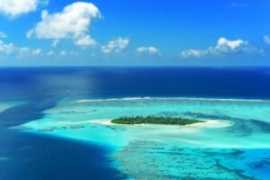 A stunning aerial view captures a lush island surrounded by turquoise waters in the Maldives.