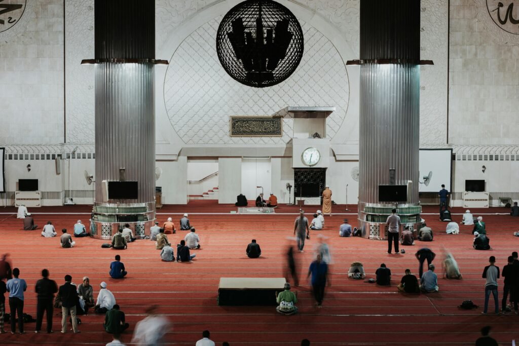 Worshippers gathered in a grand mosque for prayer, showcasing Islamic architecture and community gathering.